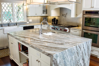 Kitchen - large transitional l-shaped dark wood floor kitchen idea in Other with a farmhouse sink, shaker cabinets, white cabinets, quartzite countertops, gray backsplash, glass tile backsplash, stainless steel appliances and an island