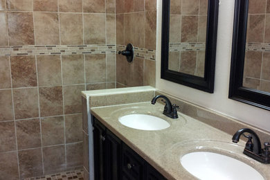 Inspiration for a large timeless master brown tile and porcelain tile porcelain tile and beige floor alcove shower remodel in Orlando with dark wood cabinets, furniture-like cabinets, a two-piece toilet, brown walls, an undermount sink, quartz countertops, a hinged shower door and beige countertops
