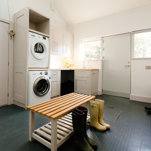 Design ideas for a traditional l-shaped utility room in Cornwall with a stacked washer and dryer, shaker cabinets, white cabinets, wood worktops, white walls, lino flooring and beige worktops.