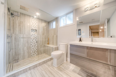 Example of a mid-sized transitional 3/4 beige tile and porcelain tile porcelain tile and beige floor alcove shower design in Toronto with flat-panel cabinets, beige cabinets, a one-piece toilet, beige walls, an integrated sink, solid surface countertops, a hinged shower door and white countertops