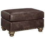 Signature Design by Ashley - Nicorvo Coffee Ottoman - Enticing with a coffee brown faux leather, beautified with a gently weathered effect and designer stitching, this ottoman merges a richly traditional sense of style with modern comfort. Turned bun feet and prominent nailhead trim incorporate distinctive character.