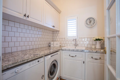 Small traditional l-shaped dedicated laundry room in Perth with a drop-in sink, raised-panel cabinets, white cabinets, marble benchtops, white walls, medium hardwood floors and a side-by-side washer and dryer.