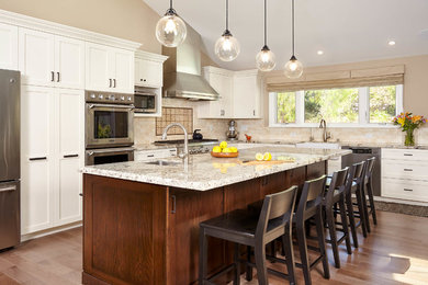 Inspiration for a huge transitional l-shaped medium tone wood floor open concept kitchen remodel in San Francisco with a farmhouse sink, shaker cabinets, beige backsplash, porcelain backsplash, stainless steel appliances and an island