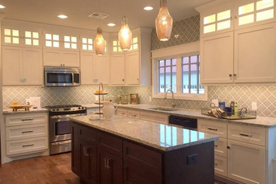 Eat-in kitchen - mid-sized traditional l-shaped medium tone wood floor eat-in kitchen idea in Oklahoma City with an undermount sink, shaker cabinets, white cabinets, granite countertops, gray backsplash, stainless steel appliances and an island