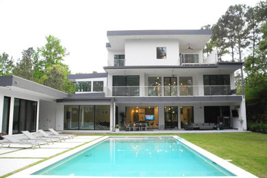 Modelo de fachada de casa blanca y blanca moderna extra grande de tres plantas con revestimiento de estuco, tejado plano y tejado de metal