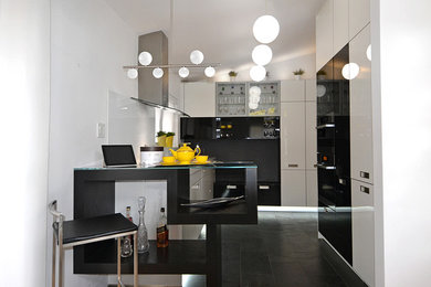 Eat-in kitchen - mid-sized contemporary galley slate floor and black floor eat-in kitchen idea with a single-bowl sink, glass-front cabinets, white cabinets, quartzite countertops, white backsplash, glass sheet backsplash, paneled appliances, no island and white countertops