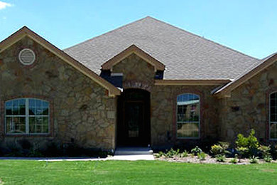 Large brown two-story stone exterior home photo in Austin