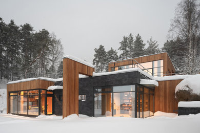Bild på ett stort funkis hus, med två våningar, blandad fasad, platt tak och tak i mixade material