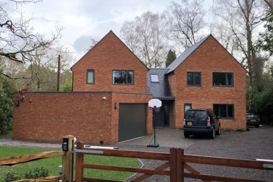Imagen de fachada de casa gris actual de tamaño medio de dos plantas con revestimiento de ladrillo, tejado a dos aguas y tejado de teja de barro