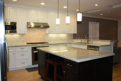 Arts and crafts light wood floor kitchen photo in San Francisco with an undermount sink, raised-panel cabinets, white cabinets, quartzite countertops, beige backsplash, stone tile backsplash, stainless steel appliances and an island