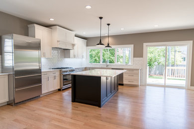 Open concept kitchen - huge country l-shaped light wood floor open concept kitchen idea in Chicago with an undermount sink, recessed-panel cabinets, white cabinets, quartzite countertops, white backsplash, subway tile backsplash, stainless steel appliances and an island
