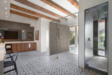 Walk-in shower - large modern master cement tile cement tile floor and multicolored floor walk-in shower idea in Phoenix with flat-panel cabinets, medium tone wood cabinets, solid surface countertops, white walls, an undermount sink and a hinged shower door