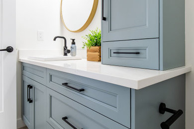 Mid-sized beach style white tile and stone slab ceramic tile, beige floor and single-sink bathroom photo in Calgary with shaker cabinets, blue cabinets, a one-piece toilet, white walls, a drop-in sink, quartz countertops, white countertops and a built-in vanity