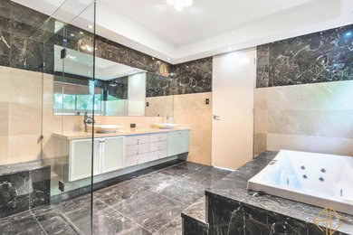 シドニーにある広いコンテンポラリースタイルのおしゃれな浴室 (ドロップイン型浴槽、洗い場付きシャワー、ベージュのタイル、大理石タイル、大理石の床、大理石の洗面台、黒い床、オープンシャワー、ベージュのカウンター、洗面台2つ、フローティング洗面台) の写真