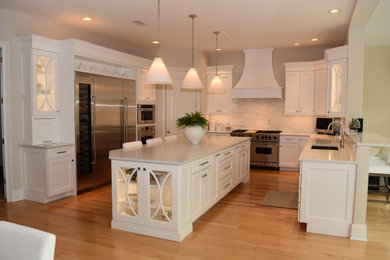 Example of a large transitional u-shaped light wood floor and brown floor eat-in kitchen design in Philadelphia with an undermount sink, recessed-panel cabinets, white cabinets, quartzite countertops, white backsplash, subway tile backsplash, stainless steel appliances, an island and white countertops