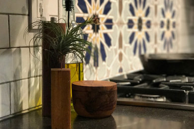 Inspiration for a large craftsman l-shaped ceramic tile and beige floor eat-in kitchen remodel in San Francisco with an undermount sink, flat-panel cabinets, medium tone wood cabinets, granite countertops, white backsplash, ceramic backsplash, stainless steel appliances, an island and black countertops