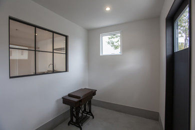 Cette image montre une entrée minimaliste de taille moyenne avec un couloir, un mur blanc, sol en béton ciré, une porte simple, une porte noire, un sol gris, un plafond en papier peint et du papier peint.