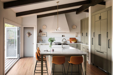 Inspiration for a mid-sized mid-century modern l-shaped medium tone wood floor, brown floor and exposed beam eat-in kitchen remodel in Denver with an undermount sink, shaker cabinets, green cabinets, quartz countertops, white backsplash, quartz backsplash, stainless steel appliances, an island and white countertops
