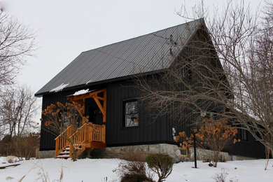 Mid-sized farmhouse black two-story wood house exterior idea in Ottawa with a shed roof and a metal roof