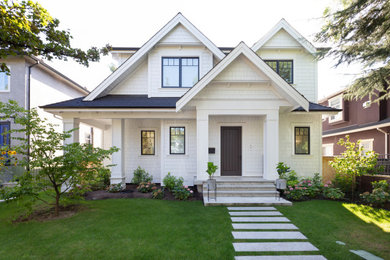 This is an example of a large transitional two-storey white house exterior in Vancouver with wood siding, a shingle roof and a gable roof.