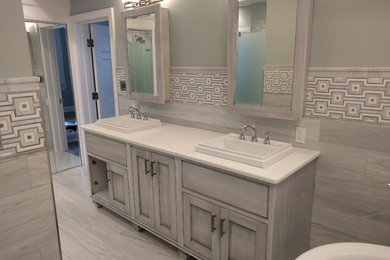 Large elegant master gray tile and stone tile marble floor bathroom photo in Huntington with recessed-panel cabinets, gray cabinets, a one-piece toilet, green walls, a vessel sink and quartzite countertops