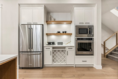 Open concept kitchen - modern u-shaped medium tone wood floor and brown floor open concept kitchen idea in Calgary with shaker cabinets, white cabinets, quartz countertops, white backsplash, quartz backsplash, stainless steel appliances, an island and white countertops