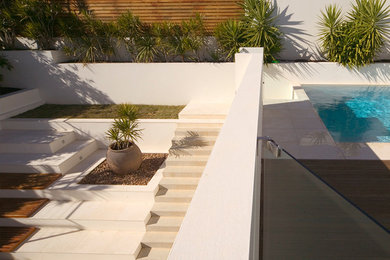 Photo of a contemporary rectangular aboveground pool in Sydney with natural stone pavers.