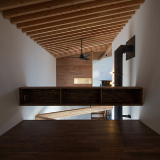 Idee per una camera da letto stile loft etnica di medie dimensioni con pareti bianche, parquet scuro, stufa a legna, cornice del camino in cemento e pavimento marrone