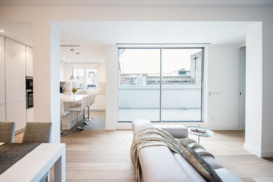 Example of a large minimalist open concept light wood floor living room design in Madrid with white walls and a wall-mounted tv