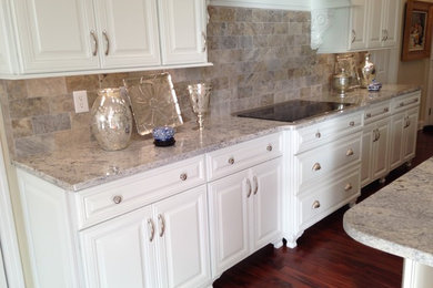 Inspiration for a large timeless galley dark wood floor eat-in kitchen remodel in Nashville with raised-panel cabinets, white cabinets, granite countertops, gray backsplash, stone tile backsplash, stainless steel appliances and an island