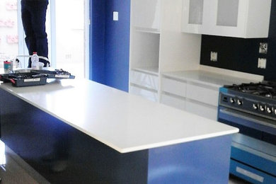 Example of a mid-sized minimalist single-wall porcelain tile eat-in kitchen design in Other with an undermount sink, flat-panel cabinets, white cabinets, granite countertops, blue backsplash, colored appliances and an island