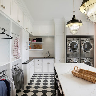 Photo of a traditional u-shaped utility room in Minneapolis with a submerged sink, shaker cabinets, white cabinets, pink walls, a stacked washer and dryer and white worktops.