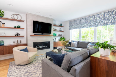 Mid-sized minimalist open concept light wood floor and blue floor living room photo in Chicago with white walls, a standard fireplace, a tile fireplace and a wall-mounted tv