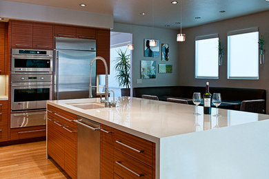 Inspiration for a large contemporary l-shaped bamboo floor eat-in kitchen remodel in Las Vegas with an undermount sink, flat-panel cabinets, medium tone wood cabinets, quartz countertops, beige backsplash, stone tile backsplash, stainless steel appliances and an island