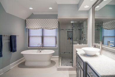 This is an example of a large transitional master bathroom in Charlotte with a freestanding tub, a vessel sink, shaker cabinets, blue cabinets, a corner shower, beige tile, porcelain tile, blue walls, porcelain floors, engineered quartz benchtops and white benchtops.