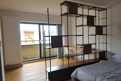 This is an example of a large contemporary guest bedroom in London with white walls and light hardwood floors.