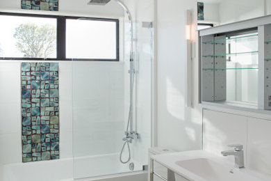 Example of a mid-sized minimalist white tile and porcelain tile porcelain tile bathroom design in Orange County with furniture-like cabinets, medium tone wood cabinets, a one-piece toilet, white walls, an integrated sink and white countertops