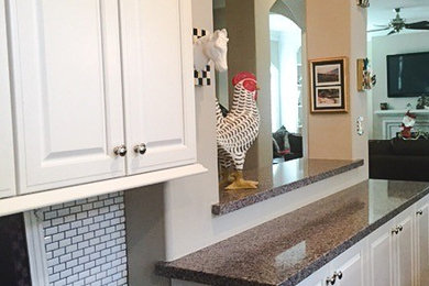 Inspiration for a cottage medium tone wood floor eat-in kitchen remodel in Houston with granite countertops, white backsplash and ceramic backsplash