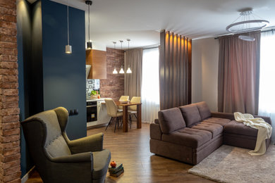 Стильный дизайн: маленькая гостиная комната в современном стиле с с книжными шкафами и полками, синими стенами, полом из ламината, телевизором на стене, зоной отдыха, коричневым полом и акцентной стеной для на участке и в саду - последний тренд