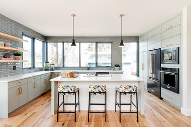 Example of a mid-century modern light wood floor, brown floor and exposed beam kitchen design in Other with flat-panel cabinets, green cabinets, quartz backsplash and white countertops