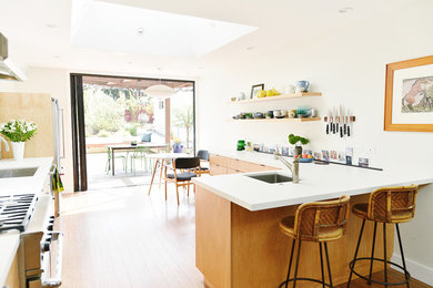 Eat-in kitchen - mid-sized 1950s bamboo floor and brown floor eat-in kitchen idea in Phoenix with an undermount sink, flat-panel cabinets, medium tone wood cabinets, quartz countertops, multicolored backsplash, cement tile backsplash, stainless steel appliances and a peninsula