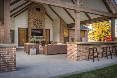 Example of a large classic backyard concrete patio design in Oklahoma City with a fire pit and a roof extension