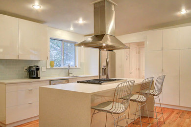 Inspiration for a mid-sized modern galley medium tone wood floor kitchen pantry remodel in Seattle with an undermount sink, flat-panel cabinets, white cabinets, blue backsplash, subway tile backsplash, an island, laminate countertops and stainless steel appliances