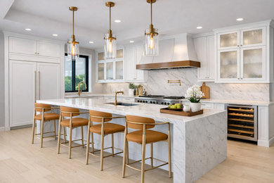 Inspiration for a huge transitional l-shaped light wood floor and vaulted ceiling eat-in kitchen remodel in Minneapolis with a drop-in sink, shaker cabinets, white cabinets, marble countertops, white backsplash, marble backsplash, stainless steel appliances, an island and white countertops