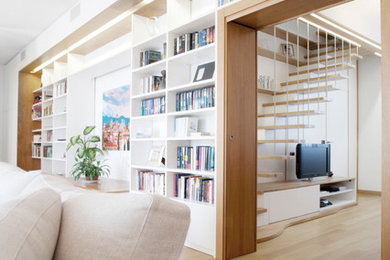 Immagine di un grande soggiorno moderno aperto con libreria, pareti bianche, parquet chiaro, camino classico, cornice del camino in pietra, TV autoportante e pavimento marrone