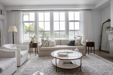 Mid-sized open concept medium tone wood floor, brown floor and wainscoting living room photo in Vancouver with white walls, a standard fireplace, a stone fireplace and a wall-mounted tv