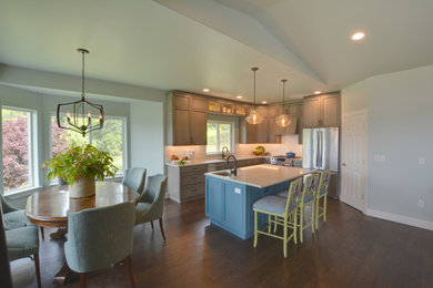 Example of a l-shaped brown floor eat-in kitchen design in Seattle with an undermount sink, raised-panel cabinets, light wood cabinets, quartzite countertops, white backsplash, porcelain backsplash, stainless steel appliances, an island and white countertops