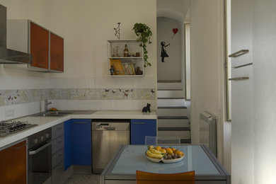 Design ideas for a small modern l-shaped eat-in kitchen in Naples with a drop-in sink, glass-front cabinets, orange cabinets, laminate benchtops, white splashback, ceramic splashback, stainless steel appliances, marble floors, no island, multi-coloured floor and white benchtop.