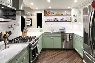Example of a mid-sized transitional u-shaped vinyl floor and multicolored floor enclosed kitchen design in Orange County with an undermount sink, recessed-panel cabinets, green cabinets, quartz countertops, white backsplash, quartz backsplash, stainless steel appliances, no island and white countertops