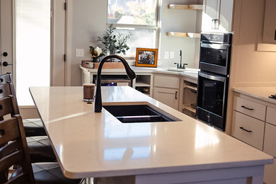 Inspiration for a large transitional l-shaped ceramic tile and brown floor eat-in kitchen remodel in Oklahoma City with a double-bowl sink, flat-panel cabinets, white cabinets, quartz countertops, gray backsplash, ceramic backsplash, stainless steel appliances, an island and white countertops